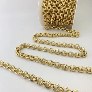 Makrodetail einer goldenen Rolo-Kette mit gravierter Textur auf einer weißen Spule