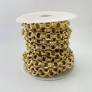 Detail einer goldenen Metallkette mit geprägten Totenkopfmustern auf einer Spule