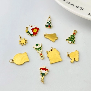 Detail of Christmas charms featuring colorful enamel snow house, tree and bell on gold base