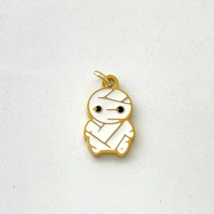 Detailed macro shot of a creative white enamel mummy pendant with gold metal plating