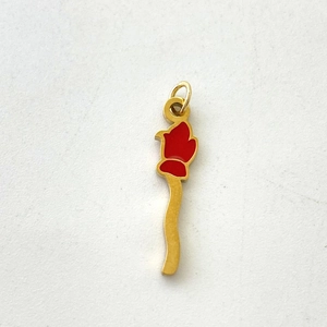 Detailed view of the wavy gold metal pendant with vibrant red enamel flower bud tip