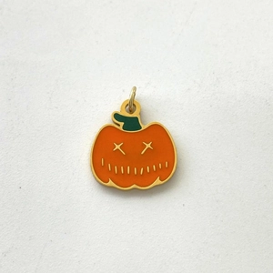 Detail showing an orange pumpkin pendant with golden edges and a green stem for Halloween