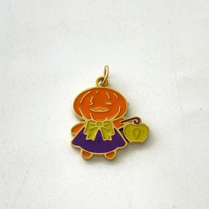 Detail of handcrafted enamel pumpkin ghost pendant with orange and purple colors