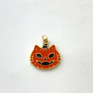 Macro detail of pumpkin and cat head pendant with orange and black enamel finish