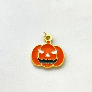 Detailed macro view of orange enamel Halloween pumpkin charm with golden metal finish