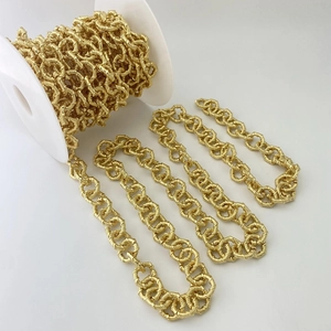 Makroaufnahme einer goldenen Gliederkette auf Rolle mit feiner Webtextur für DIY-Schmuck