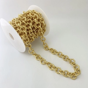 Makroaufnahme goldener strukturierter Rundglieder auf Spule für DIY Schmuckherstellung