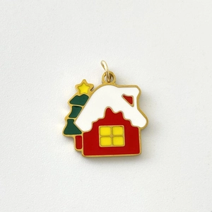 Macro view of Christmas enamel charm with red snow cottage and green holiday tree