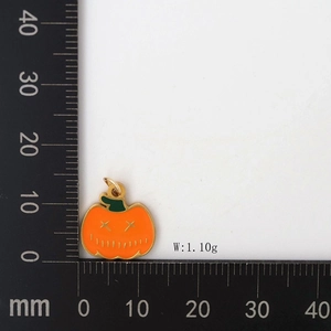 Detail of orange pumpkin pendant with gold trim, size 15mm and weight 1.10g on a scale