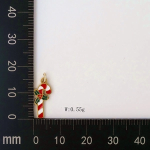 Detail of red and white candy cane pendant with holly leaf on a measuring ruler scale