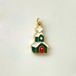 Macro detail of a Christmas house pendant with green enamel and white snow roof decor