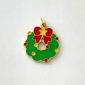 Close-up of green enamel Christmas wreath pendant with red bow and gold star detail
