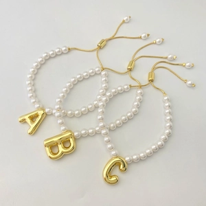 Three-piece set of white pearl bracelets with gold 3D balloon alphabet charms A, B, and C