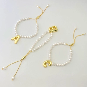 Detail of adjustable pearl bracelets with gold-tone letters A, B, and C charms