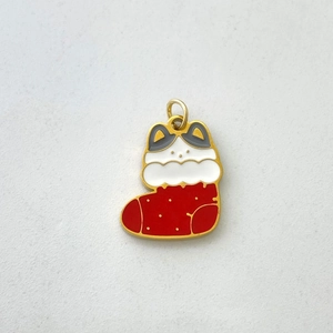 Detailed macro view of a Christmas stocking and white cat enamel pendant charm