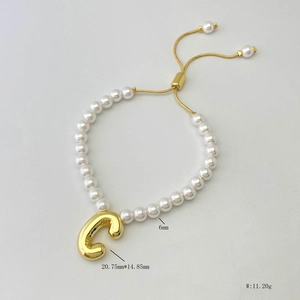 Detail of adjustable pearl bracelet featuring a 3D bubble style letter C gold pendant