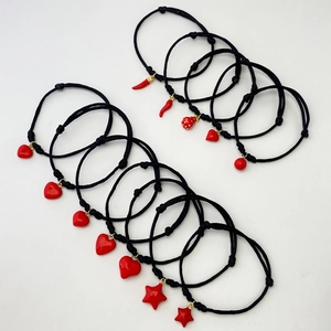 Close-up showing various red heart and fruit charms on black woven adjustable ropes
