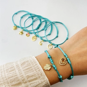 Macro shot of blue braided bracelets with gold micro-pave zircon charms and adjustable cords