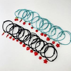 Handmade woven cord bracelets with red heart star and fruit charms on white background