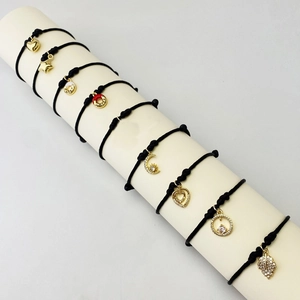 Detailed macro shot of diverse black woven rope bracelets with gold crystal charms