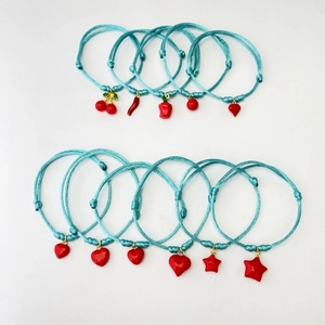 Detail of 11 handmade blue woven bracelets with various red enamel fruit and heart charms