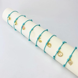 Detailed view of lake blue braided rope bracelets with various gold micro-pave pendants