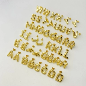 Close-up of 3D puffy gold balloon alphabet stud earrings A-Z in a neat group layout