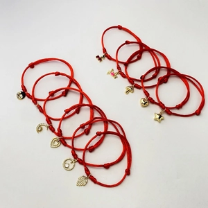 Detailed collection of red braided bracelets with various gold cubic zirconia charms