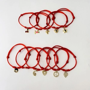 Detail of assorted adjustable red rope bracelets with gold zircon-studded charms
