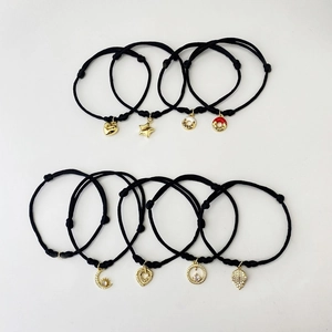 Collection of black woven adjustable bracelets with gold charms like stars and moons