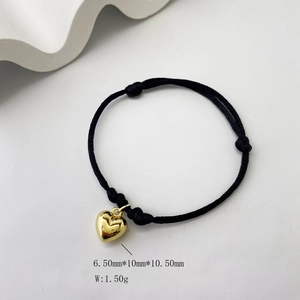 Close-up of gold heart pendant on adjustable black cord bracelet with size measurements