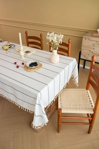 Close-up of Nordic linen tablecloth featuring blue geometric stripes and white tassels