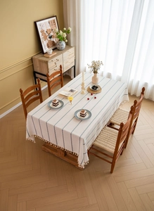 Detailed view of Nordic beige tablecloth featuring blue wavy stripes and fringe tassels