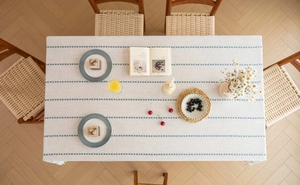 Detail of rectangular grey tablecloth with blue geometric stripes and fringe texture