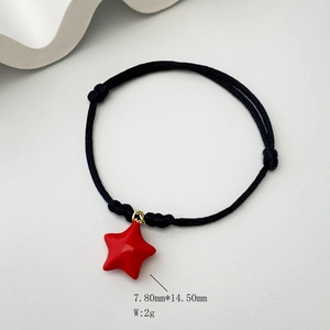 Detailed macro view of black braided rope bracelet with a red five-pointed star charm
