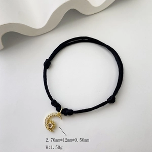 Detail view of cz moon and sun pendant on black cord bracelet showing size 12mm x 9.5mm