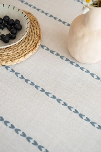 Detail of Nordic linen tablecloth featuring blue leaf embroidery and natural fiber texture