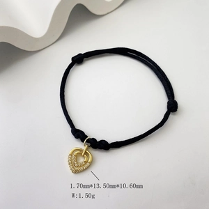 Detail view showing micro-pave zircon heart pendant on black braided rope bracelet