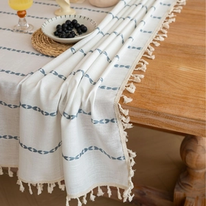 Nordic style table runner with blue patterns and fringe on a wooden dining table