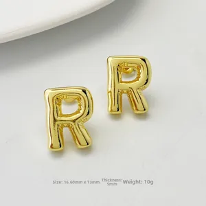 Macro detail of gold letter R stud earrings with 16.60mm size and polished finish