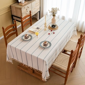 Nordic style rectangular beige tablecloth with blue stripes and white tassels on a table