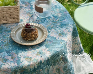 Detailed blue floral jacquard tablecloth texture with lace ruffle in outdoor garden setting