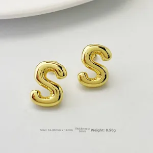 Detailed close-up of 3D balloon-style letter S gold stud earrings with polished finish