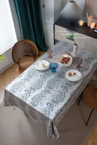 Detail of grey jacquard tablecloth showing embossed water drop texture and white tassels