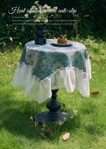 Close-up of blue floral table cloth with white lace ruffle edge on an outdoor round table