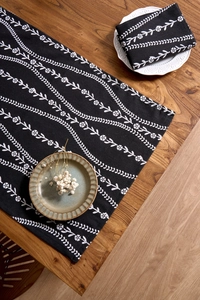 Detail of Nordic floral print cotton linen table runner on a rustic wooden dining table