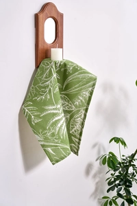 French country style green linen napkin with white leaf prints hanging on a wooden frame