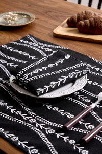 Detailed view of black floral cotton linen placemat and napkin set on wooden table