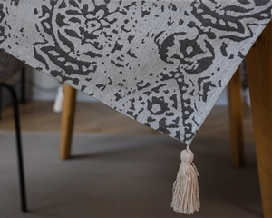 Detail of grey Nordic jacquard tablecloth showing fabric texture and cream tassels