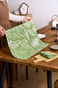 Detail of French country green maple leaf print cotton linen napkin on a wooden table
